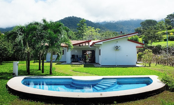 A tranquil house nestled in greenery, featuring a beautiful pool.