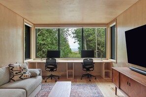 A workspace with dual monitors overlooking lush greenery and the water beyond, creating a perfect balance of productivity and relaxation.