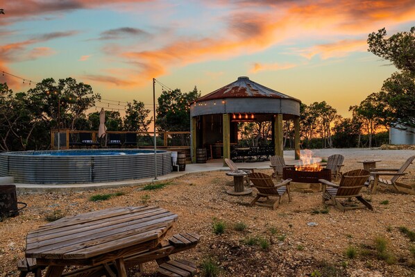Stock tank pool with firepit and outdoor dining under the pavilion