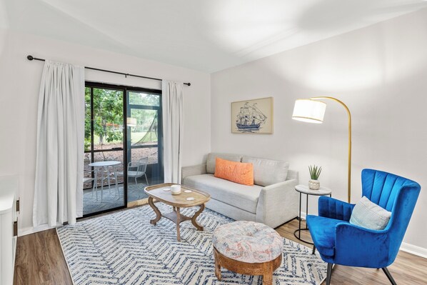The living room offers a cozy seating area, a smart TV, and access to a private screened porch with tranquil outdoor views.