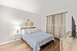 Bedroom 1 features a comfortable queen bed and is equipped with a smart TV, providing a cozy retreat for relaxation and entertainment.