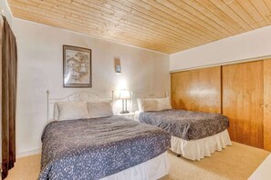 Room provides cozy beds (2 queens), ample storage with a built-in closet, nightstand, dresser, as well as warm lighting, and a minimalist design perfect for relaxation.