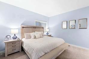 Bright modest primary room featuring a King bed, dedicated bathroom, and a television.