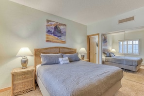 Bright modest primary room featuring a queen bed, dedicated bathroom, and closet.