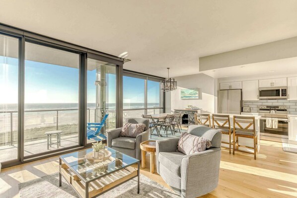 A modern, open-concept living space with large windows, cozy seating, a spacious dining area, and a bright, inviting atmosphere.