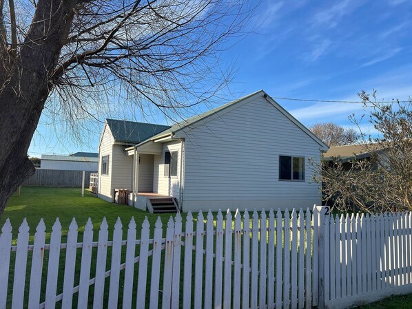 Front of home with picket fence and double gates