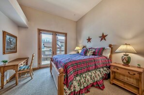 This warm and inviting bedroom offers a queen bed, traditional wooden furniture, and beautiful natural light from large windows.