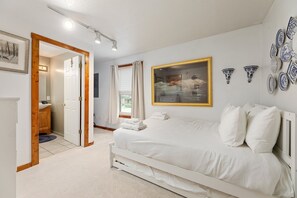 Bright and serene bedroom featuring cozy white bedding, elegant wall art, and soft lighting for a restful retreat complete with an en suite