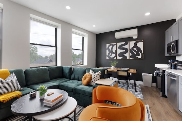 Enjoy a blend of modern comfort and style in this spacious living area. Featuring a plush sofa, chic decor, and a vibrant neon sign, it's perfect for relaxation and socializing.