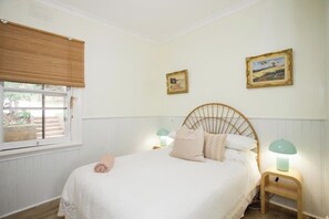 Rest in this serene bedroom, featuring a comfortable bed, charming artwork, and a touch of natural light.