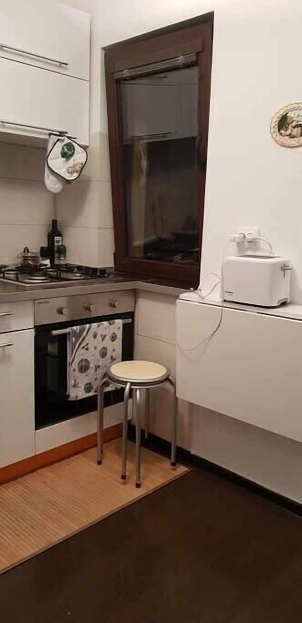 Stylish kitchen featuring a 4-burner stove, electric oven, toaster, kettle, cleaning products, basic condiments and cutlery