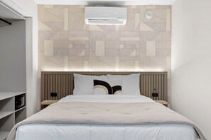The room features a unique geometric wall design and a modern air conditioning unit.