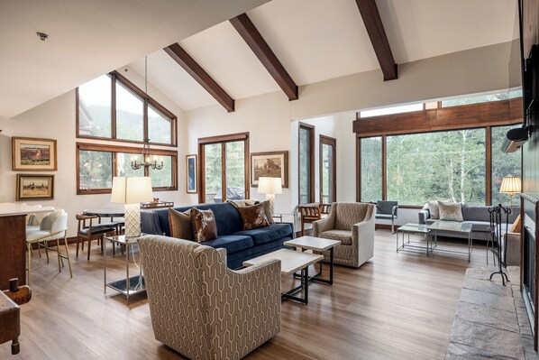 - Soak in peaceful forest views through soaring windows and warm wood accents
- Relax on cozy seating under vaulted ceilings with exposed beams and natural light
- Enjoy meals and game nights at the spacious dining table just steps from the kitchen