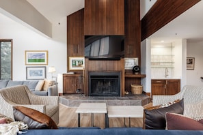 - Unwind by the stone fireplace with wood paneling and mounted TV for movie nights
- Gather in comfort with armchairs, plush pillows, and a stylish lounge setup
- Sip and socialize at the built in wet bar with glassware display and sleek faucet