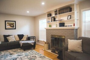 Nestled in warmth and elegance, this cozy living room features plush, inviting sofas, a crackling fireplace, and soft, ambient lighting.