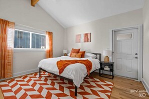 Orange and white themed main bedroom with king bed and private bathroom