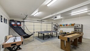Game room featuring shuffleboard, ping pong, basketball arcade game, 2 bikes, board games, and much more! Garage door can be opened on warm days.