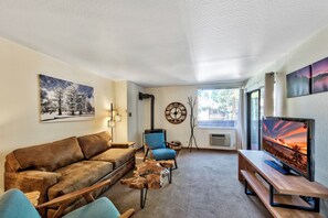 There is a wall mounted air conditioning unit and gas fireplace in the living room
