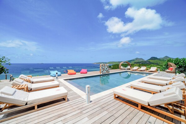 Heated pool surrounded by a spacious sun terrace with deckchairs. Panoramic views over Anse des Cayes.