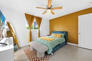 Bedroom with queen bed, ceiling fan, and room darkening shades