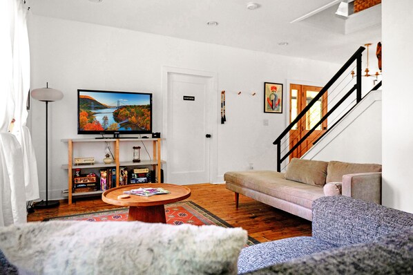 Living area with 40" Smart TV, modular sofa, coffee table, and board games.