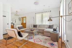 Large living room with sectional sofa, coffee table, HD projector, and speaker.