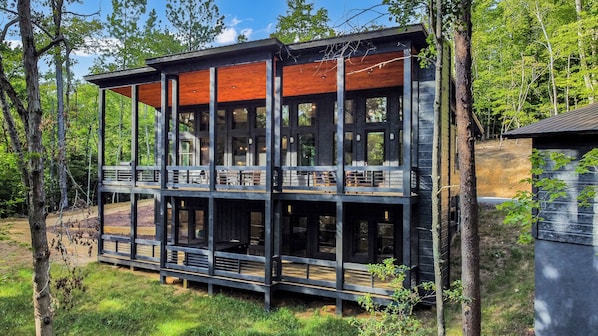 A view of the cabin exterior, highlighting a large deck that overlook the forest