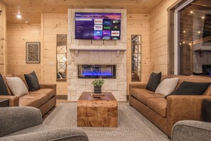 Relax in the spacious living room, featuring ample seating, a cozy and vibrant fireplace, stunning views, and a large TV for your entertainment.