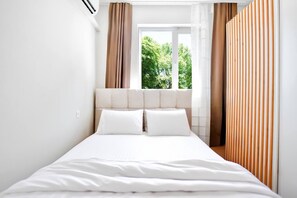 Rest peacefully in this bright and airy bedroom, where soft tones and natural light create a serene atmosphere. The comfortable bed is perfectly positioned to offer a relaxing view of the lush greenery outside.