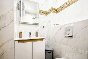 Indulge in the elegance of this modern bathroom, featuring sleek fixtures and a sophisticated marble design. The well-lit space offers both functionality and style, making your daily routines a pleasure.