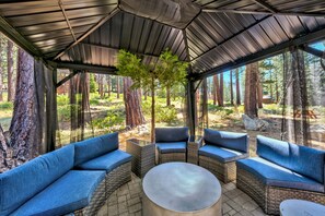 Relax in the charming gazebo surrounded by lush greenery, featuring ample comfortable seating around a cozy table—perfect for enjoying the fresh South Lake Tahoe air.