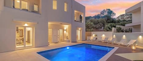 POOL | Enjoy the enchanting evening ambiance with beautiful illumination, complemented by comfortable sun loungers, umbrellas, and coffee tables.