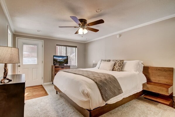 Primary bedroom with a plush king bed, ceiling fan, and private access to the outdoors.