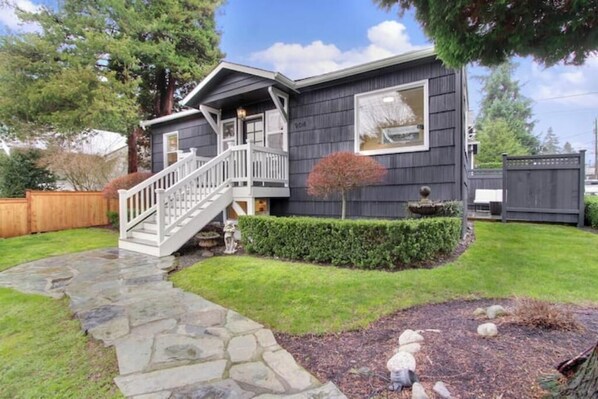 Front of home with sweet front porch, manicured gardens, and bespoke rock path
