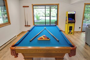 Game room with pool/ping pong, Pac-Man, PS4, smart TV, couch, and gas stove.