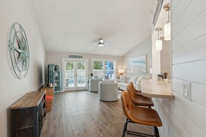 Open concept living space with sofa bed, board games, books, barstools, bar cart