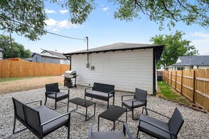 Backyard Outdoor Stone Gravel Sitting and Grill Area, with side yard dog run with new grass.