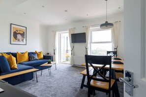 Relax in the stylish and comfortable living area, complete with plush seating, vibrant decor, and a balcony that lets in plenty of natural light and sea breeze.