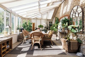 Dine in the sunlit orangery surrounded by greenery, perfect for morning coffee or evening meals