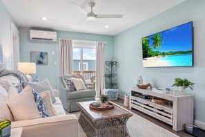 Bright coastal living room with comfy sofa, large TV & fresh ocean breeze.