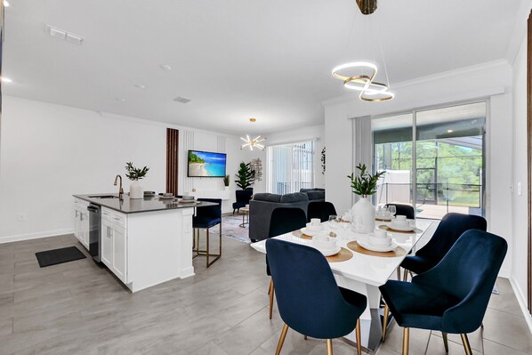 Step into this stylish living and dining space featuring modern decor, a fully equipped kitchen, and views of the private pool.