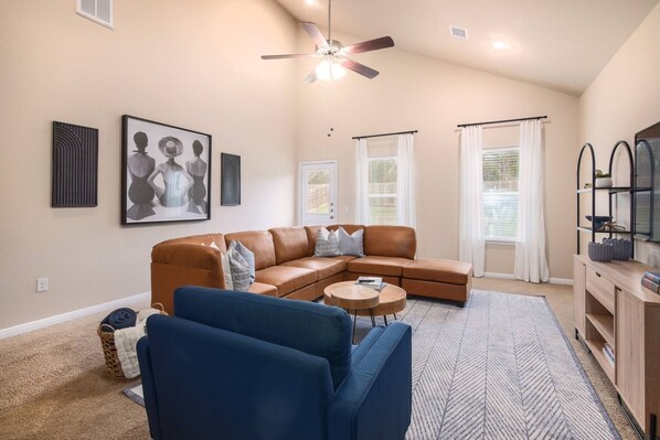 Cozy and stylish living room featuring a spacious leather sectional, modern decor, and ample natural light. Perfect for relaxation and entertainment!