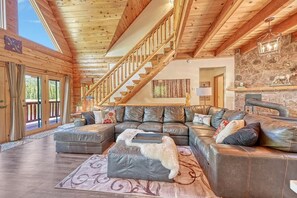 Welcoming living room featuring a large, comfortable sofa and tasteful wood accents, creating a warm and inviting atmosphere. This stylish space is perfect for relaxation and entertaining, offering a blend of comfort and natural charm. Ideal for thos