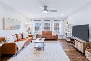 Bright and airy living room with ample natural light, cozy seating, and a TV for ultimate relaxation.