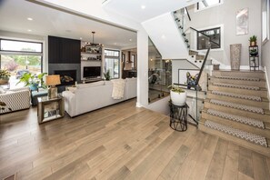Step inside and experience luxury throughout. The entryway leads to a spacious living room with sleek design. A stunning glass-railing staircase adds a modern touch, offering a sophisticated ambiance perfect for relaxation.