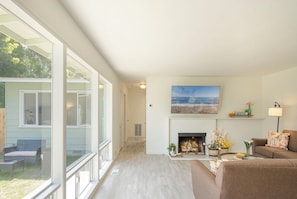 Living Room has a Gas Fireplace, TV and a Wall of Windows