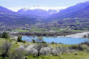 This breathtaking panoramic view showcases the serene beauty of the surrounding landscape. The crystal-clear waters of the lake shimmer in the foreground, while the charming village nestled in the valley below adds a touch of warmth to the scene. In the
