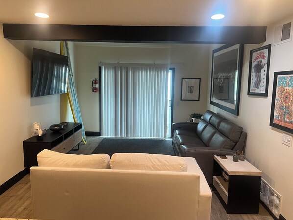 Living room with smart TV, leather couch and great surf artwork and surfboards