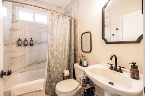 The newly updated main floor full bath features a shower-tub combo and premium Public Goods amenities. Fully stocked with Q-tips, flossers, cotton pads, lotion, and hand soap, it has everything you need for a refreshing and convenient stay.