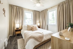 Relax in the sunlit main floor bedroom, styled with modern neutral décor. This cozy retreat features a plush queen-size bed, luxurious linens, and a premium mattress for ultimate comfort.